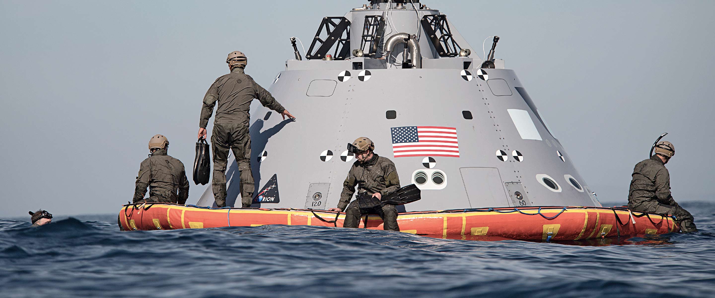 Navy Aerospace Experimental Psychologists look at a space capsule in the ocean