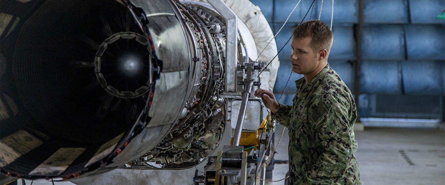 A Navy mechanical industrial tech inspects a large engine component