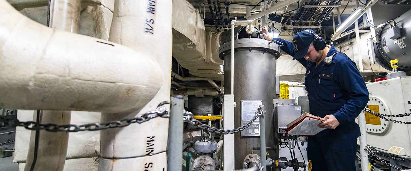 A United States Navy Engineman displaces air from the fuel separator system in the main machinery room aboard the USS Detroit.