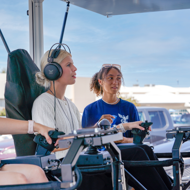  Women sits in helicopter simulator at The Strike Group experience, presented by America's Navy.