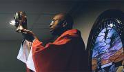 A United States Navy Chaplain raises communion wine during a service.