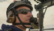 A United States Navy special operations Sailor communicates through a headpiece while standing watch on the deck of a Navy vessel.